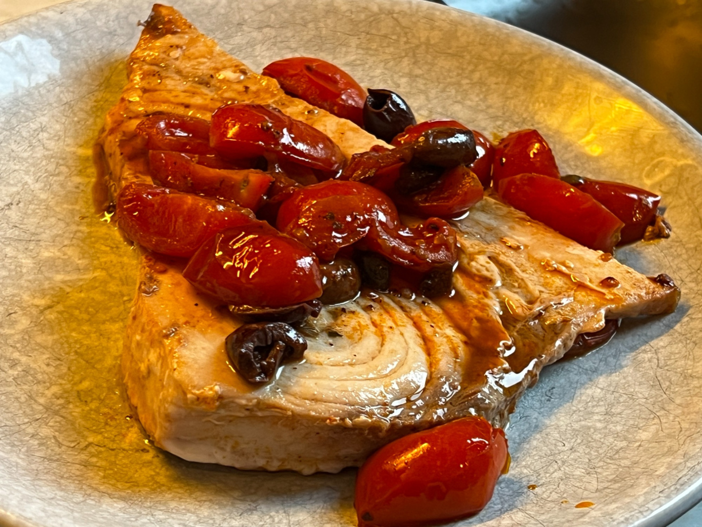 Pesce spada al burro e aglio, con pomodorini, olive e capperi